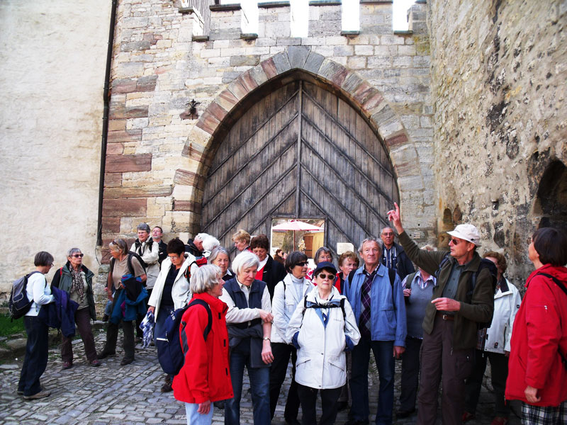 am Tor der Burg Querfurt weist Dr. Petters Kreuzigungsgruppe aus dem 15. Jhdt. hin
